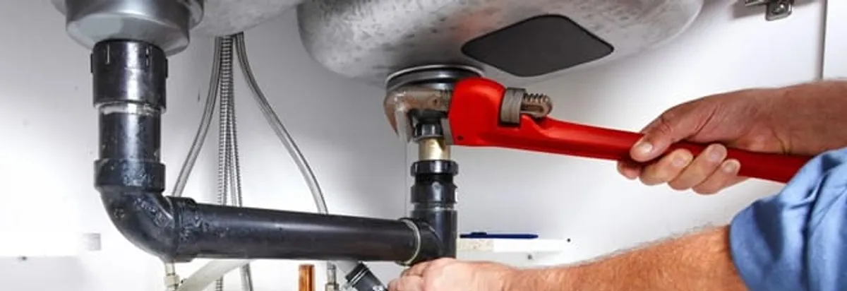 Garbage disposal repair technician tightening the sink drain and disposal connection in Wilmington, NC